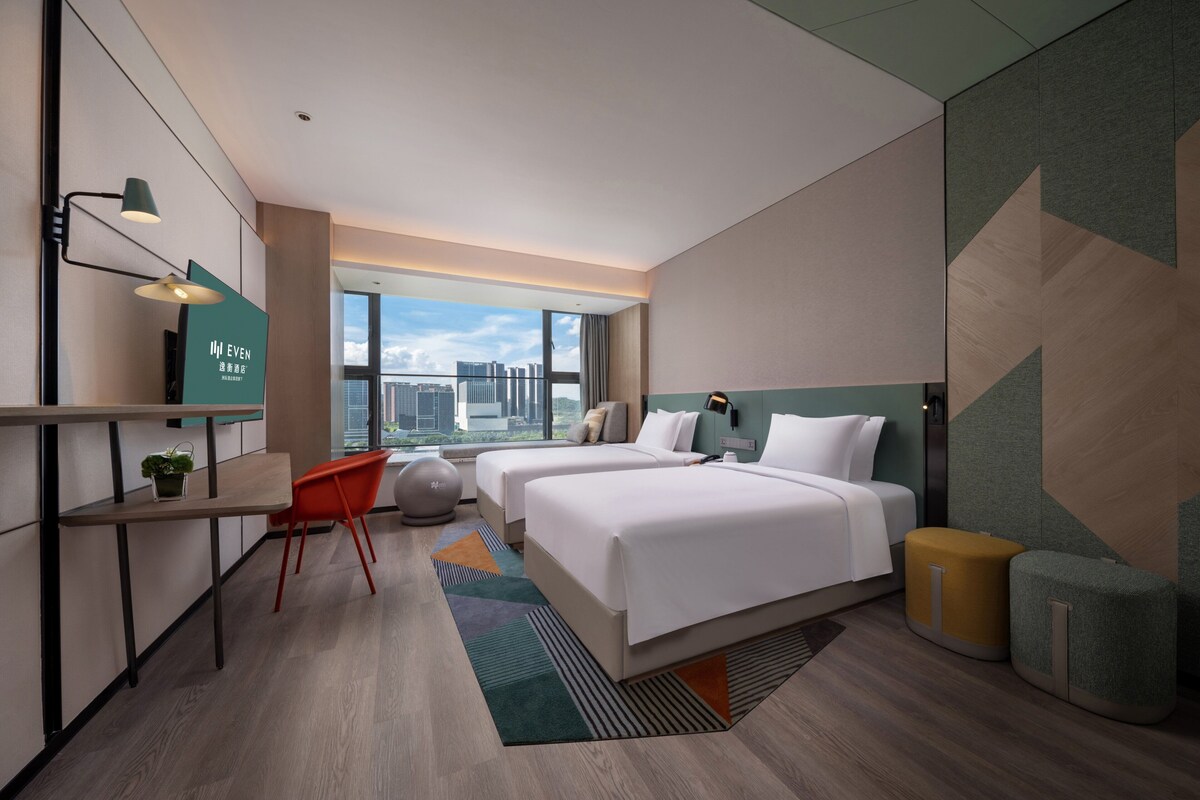 Habitación de hotel moderna con una cama grande, un escritorio y vistas a la ciudad.