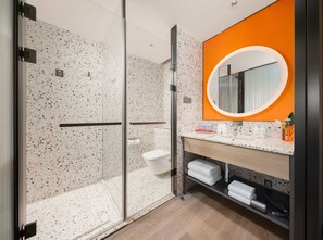 Een moderne badkamer met een douchecabine van glas, een wit toilet en een wastafel met spiegel.