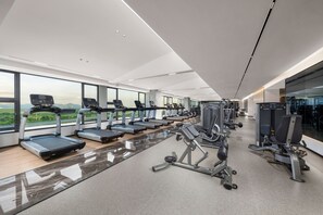 Un gimnasio moderno con cintas de correr, máquinas de pesas y vistas a la montaña.
