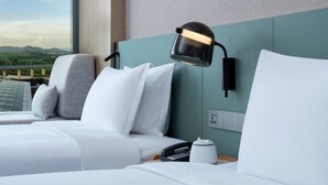 A hotel room with a bed, a nightstand, a lamp, a telephone, and a view of a bridge and mountains. - EVEN Hotel Shenzhen Guangming Cloud Park by IHG (Shenzhen)