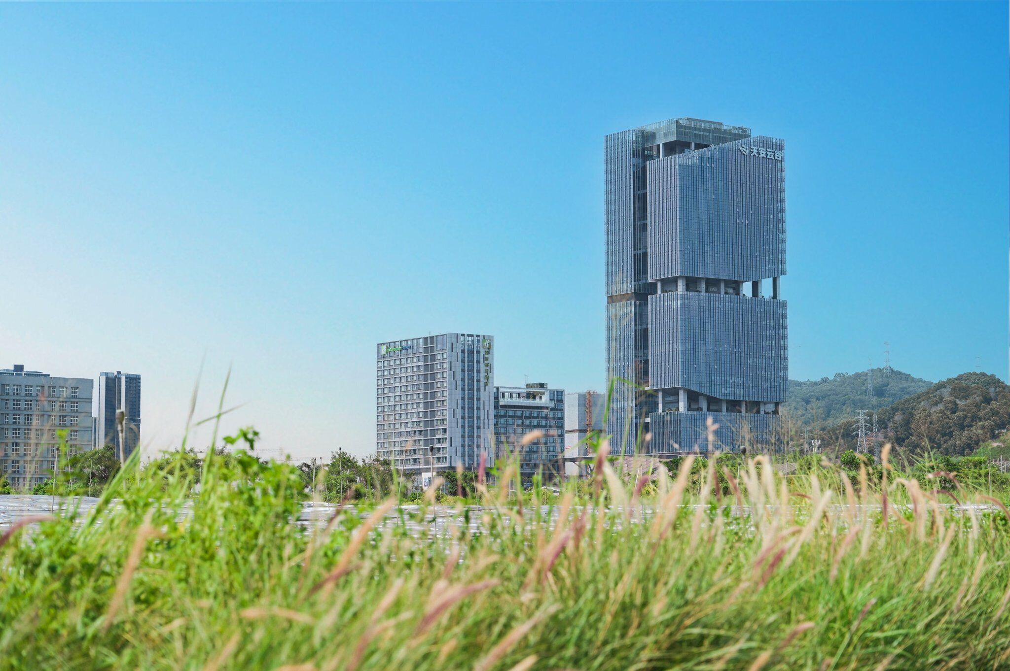 En moderne højhusbygning med et unikt arkitektonisk design, omgivet af andre bygninger og grønne områder.