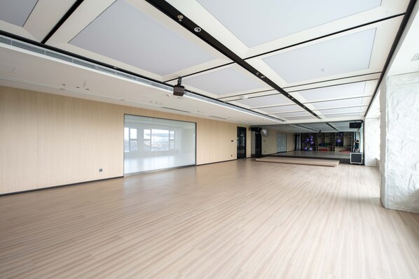 Une pièce spacieuse et moderne, dotée d’un plancher en bois, de grandes fenêtres et d’un plafond avec des spots encastrés et un projecteur.