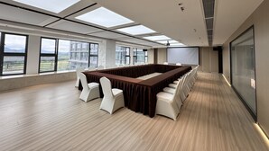 A conference room with a long table, white chairs, and large windows offering a city view. - EVEN Hotel Shenzhen Guangming Cloud Park by IHG (Shenzhen)
