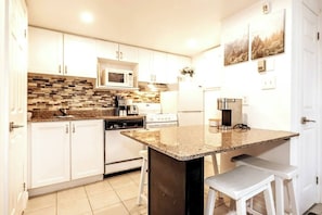 Enjoy cooking in this well-lit kitchen with a central island, microwave, stove, and dishwasher.