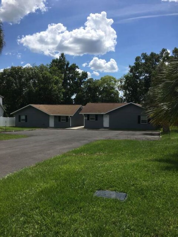 A row of two-story houses with a paved driveway and a grassy lawn.