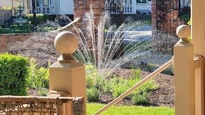 A residential property with a well-maintained garden, a fountain, and a large house in the background. - The Adams Pragge House (Port Townsend)