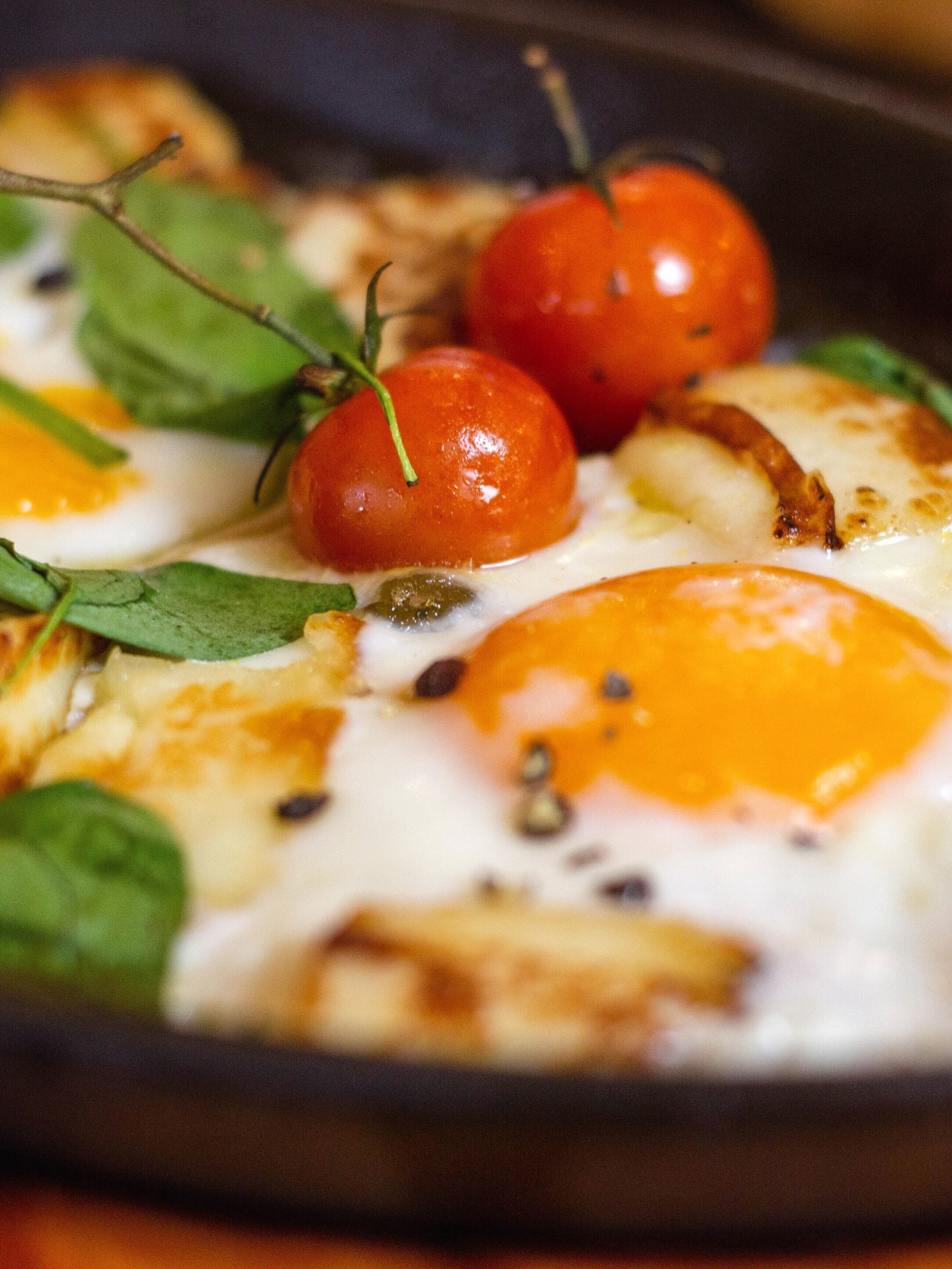 A close-up of a dish with eggs, tomatoes, and greens.
