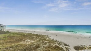 Una playa con arena, algunas personas y un edificio a la izquierda.