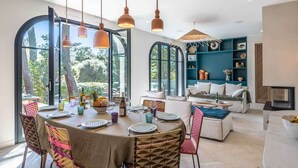A spacious dining area with a round table, chairs, and pendant lighting.