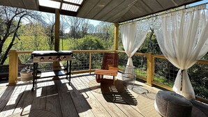 Un espacio al aire libre techado con una parrilla, un banco de madera y vistas a zonas verdes.