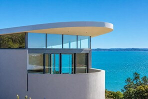 Un edificio moderno con un balcón curvo que da a una masa de agua.