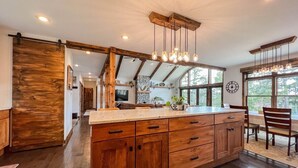 A spacious kitchen with wooden cabinets, a large island, and pendant lighting. - R&R White Mountain Retreat, Hillside with Extraordinary Views! (Fryeburg)