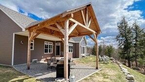 A house with a covered patio, a grill, and outdoor seating. - R&R White Mountain Retreat, Hillside with Extraordinary Views! (Fryeburg)