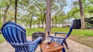 Un espace patio avec deux chaises bleues, une table en bois et une bouteille de vin.