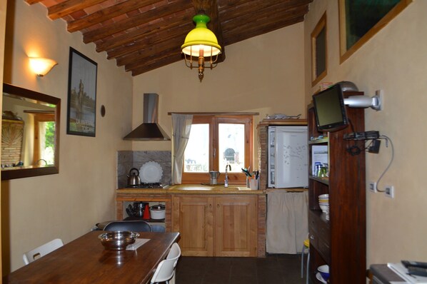 A kitchen with wooden cabinets, a stove, a sink, and a window with curtains.