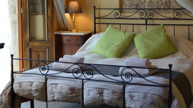 A bed with a metal frame, green pillows, and a white bedspread. There is a nightstand with a lamp and a map on the wall. - Panoramic Sea Views Immersed in Nature Quiet Peaceful Private Villa Retreat (Toscana)