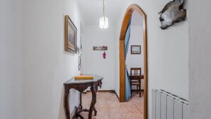 A hallway with a wooden table, a hanging light fixture, and a radiator.
