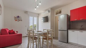 Une cuisine moderne avec des meubles blancs, un réfrigérateur rouge et un coin repas comprenant une table et des chaises.