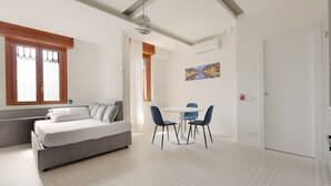 A modern bedroom with a bed, a dining area with chairs, and a painting on the wall. - GuestHost - Renovated studio apartment with all amenities! (Milano)
