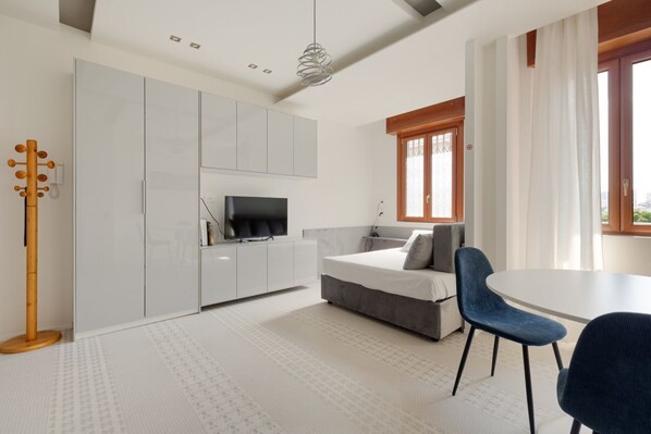 Une chambre à coucher moderne avec un lit, une télévision, un bureau et une chaise.