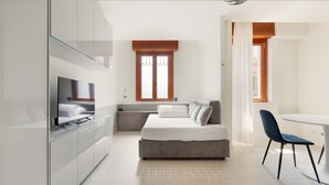A modern bedroom with a bed, a TV, a desk, and a chair. - GuestHost - Renovated studio apartment with all amenities! (Milano)