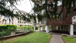 A courtyard with a stone pathway, a small garden, and a building with a balcony.