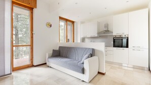 A modern kitchen with white cabinets, a built-in oven, and a window.