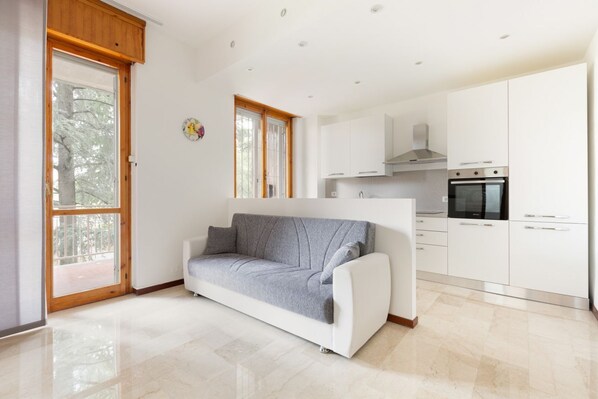 A modern kitchen with white cabinets, a built-in oven, and a window.