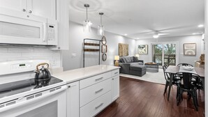 A modern kitchen with white cabinetry, a built-in microwave, and a kettle on the stove. - 2 BR/2BA w/Stunning Marsh Views! Amenity access included! (Seabrook Island)