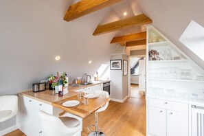Een moderne keuken met een houten aanrecht, witte kastjes en een eethoek met witte stoelen.