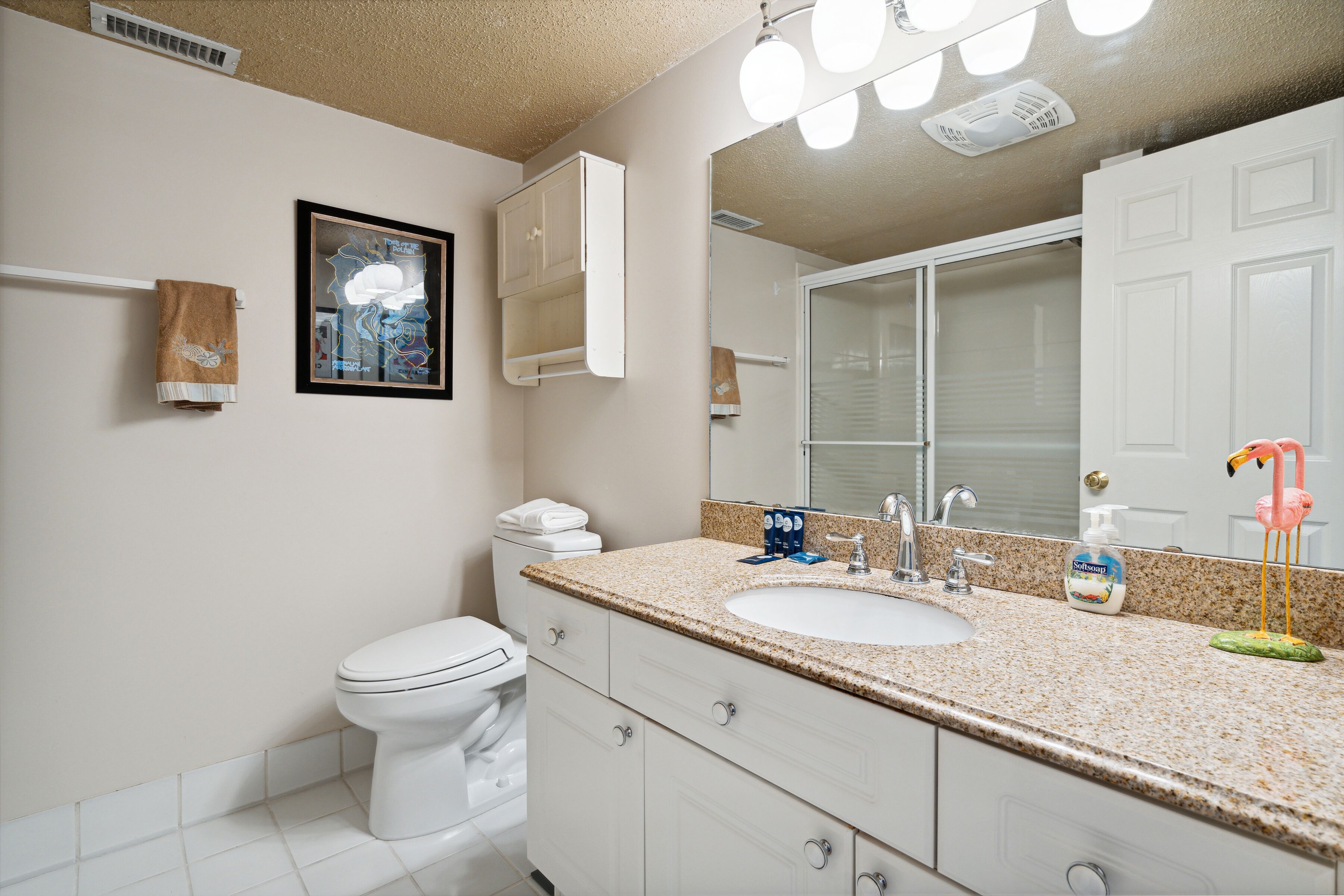 A bathroom with a white toilet, a sink with a mirror, and a towel rack.