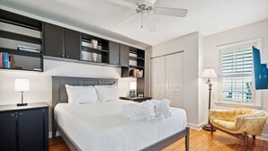 A neatly arranged bedroom with a bed, bedside tables, a wardrobe, and built-in shelving.