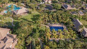 An aerial view of a residential area with multiple houses, a swimming pool, and palm trees. - Bright & quiet 2 bedroom in Kulalani, sleeps 6 (Kamuela)
