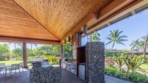 An outdoor kitchen area with a stone structure, a grill, and a dining table with chairs. - Bright & quiet 2 bedroom in Kulalani, sleeps 6 (Kamuela)
