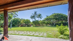 A covered outdoor area with a stone pathway leading to a grassy lawn, surrounded by lush greenery and palm trees. - Bright & quiet 2 bedroom in Kulalani, sleeps 6 (Kamuela)