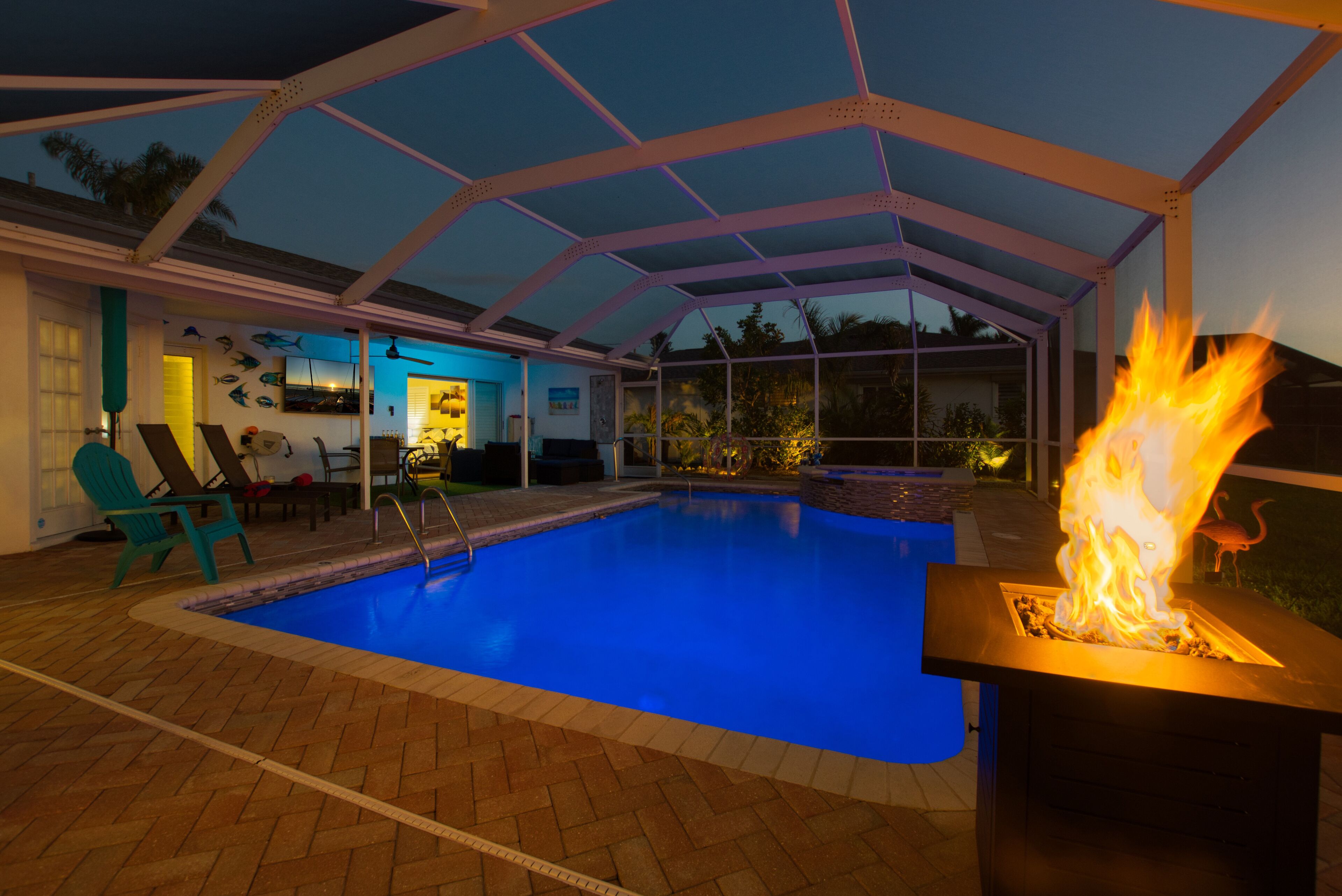 Una piscina interior con una chimenea, rodeada de sillones de descanso y un patio cubierto.