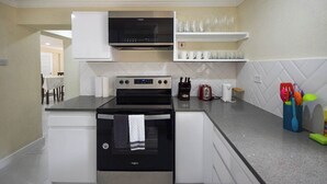 A compact kitchen with a built-in oven, microwave, and a coffee maker on the countertop. - 3 min walk to beach - Bella Figura (5 bed) (Hastings)