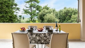 A dining table set with plates, glasses, and a bottle, overlooking a lush landscape with trees and a clear sky. - Art Beds & Garden 9 beds between the sea, thermal baths, and the Tuscan countrys (Suvereto)