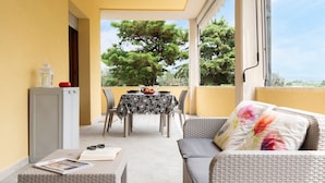 A balcony with a dining table, chairs, a sofa, and a small cabinet. - Art Beds & Garden 9 beds between the sea, thermal baths, and the Tuscan countrys (Suvereto)