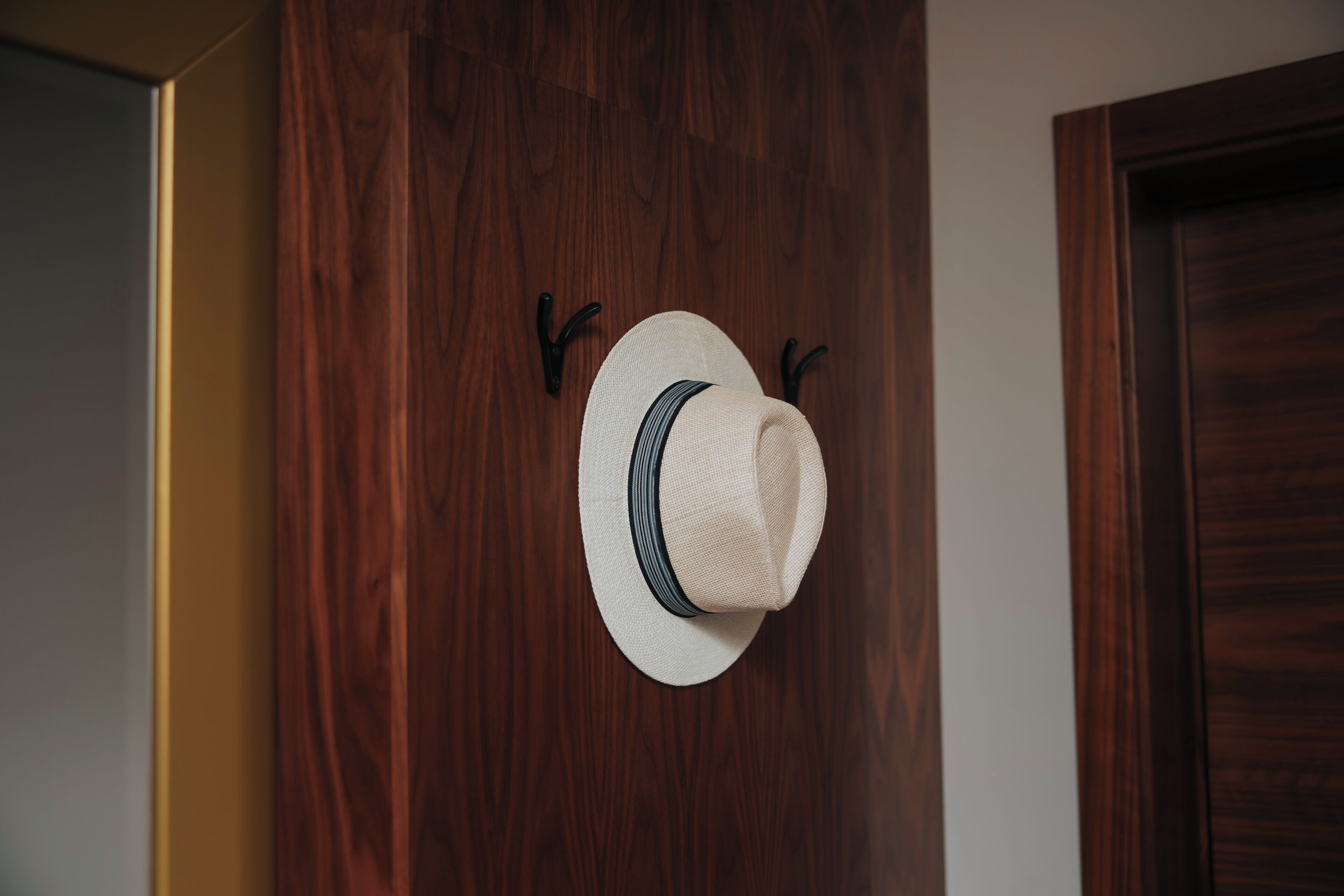 A hat hanging on a wooden wall with two hooks.
