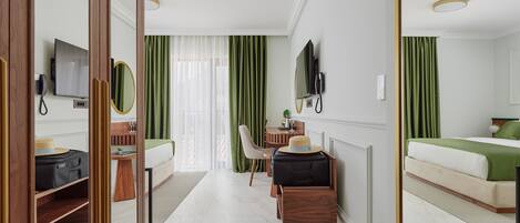 Una habitación de hotel con una cama, un escritorio con silla, un televisor y un espejo.