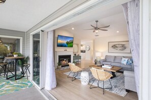 A modern living room with a fireplace, a sofa, a coffee table, and a television.