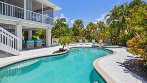 Ein Schwimmbecken mit Liegestühlen und einer überdachten Terrassenanlage.