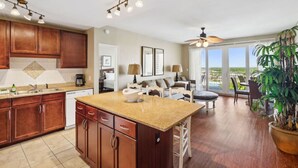 A spacious kitchen with a large island, wooden cabinets, and a dining area with a view. - 5 Pools, Gym, Beach Access at Laketown Wharf 1230 (Panama City Beach)