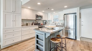 A modern kitchen with white cabinets, stainless steel appliances, and a central island with stools.