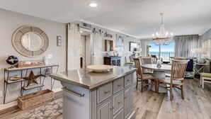 A modern kitchen with a central island, wooden chairs, and a chandelier.