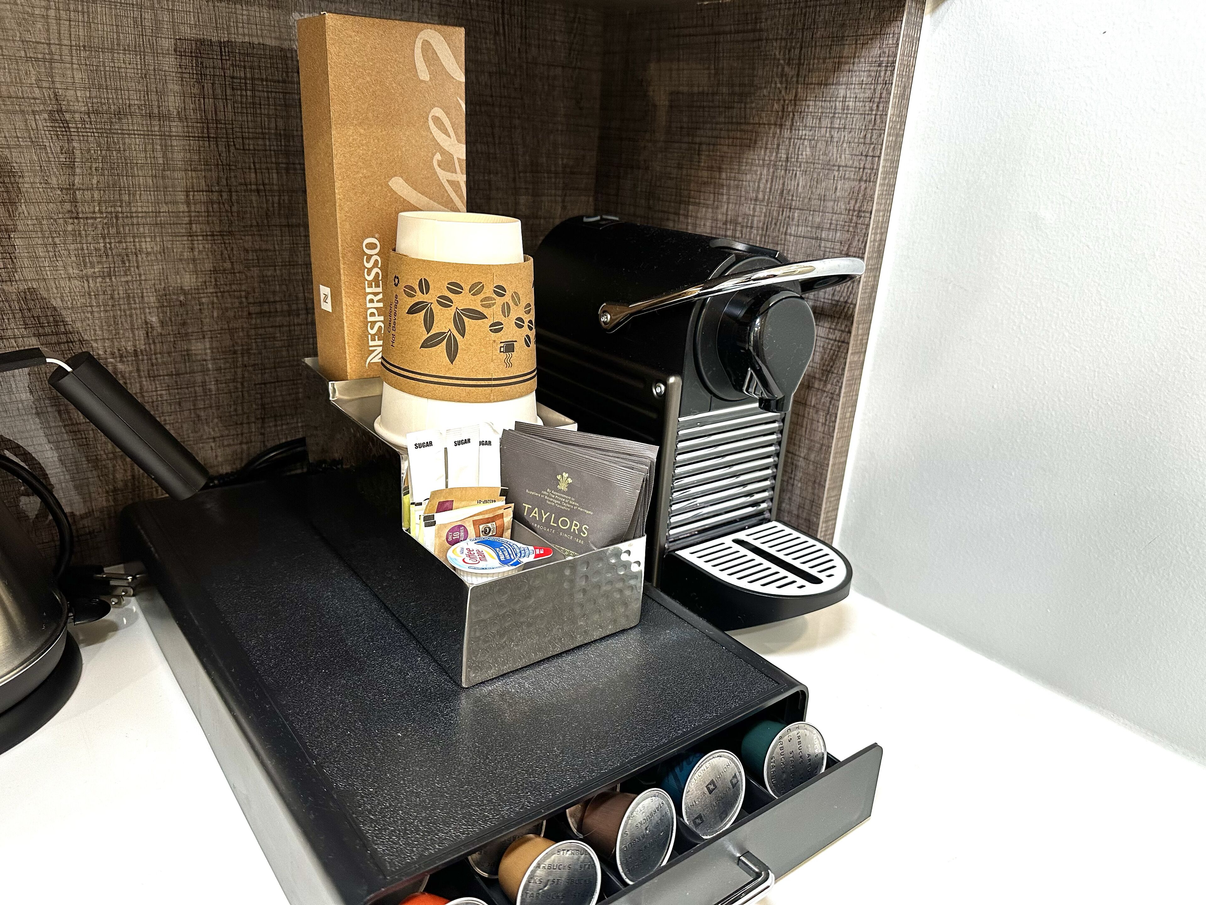 A coffee machine with a paper cup holder, a coffee grinder, and a coffee maker.