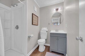 Une salle de bain équipée d’une douche, de toilettes, d’un lavabo et d’un miroir.