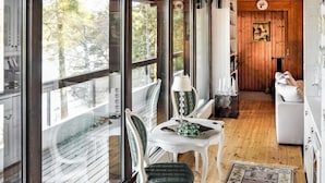 Ein gemütliches Zimmer mit Holzboden, einem weißen Sofa, einem Tisch mit einer Lampe und einem Sessel.