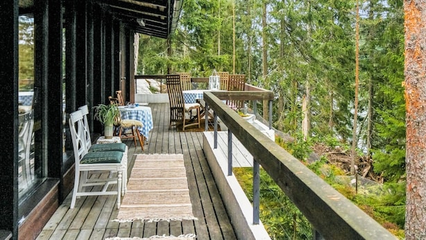 Eine Holzterrasse mit Sitzgelegenheiten, umgeben von dichtem Wald.